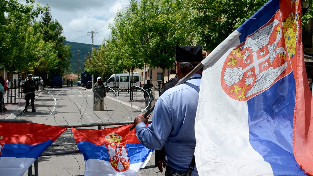 Mann hält serbische Fahne im Kosovo, KFOR-Einheit
