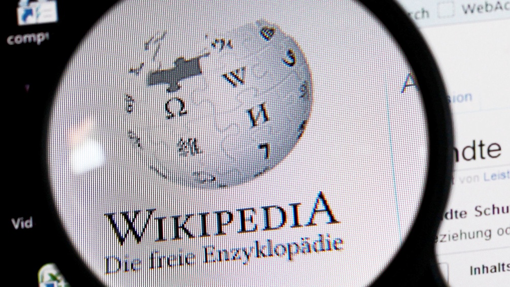 Durch eine Lupe sehen wir das Wikipedia Logo