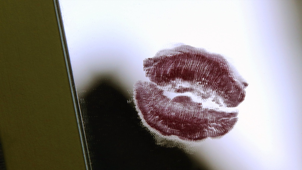 Der Lippenstiftabdruck eines Kussmundes auf einer Glasscheibe.