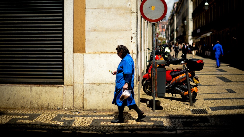 Frau geht in Lissabon auf der Straße, schaut auf ihr Handy