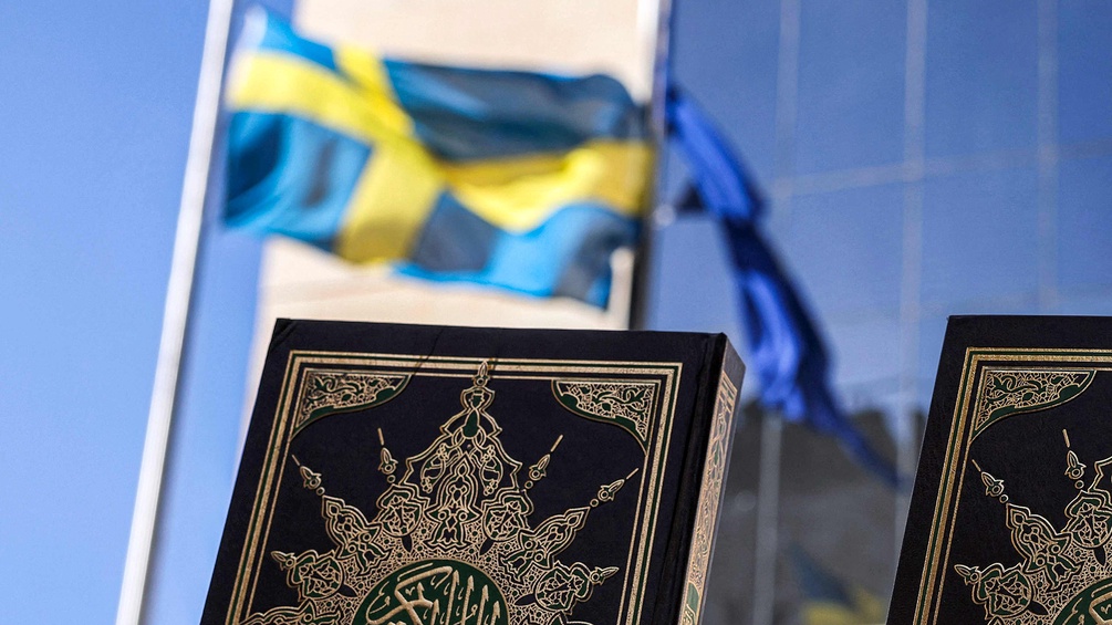 PICTUREDESK.COM/AFP/HAZEM BADER Die schwedische Flagge im Hintergrund, im Vordergrund zwei Korane