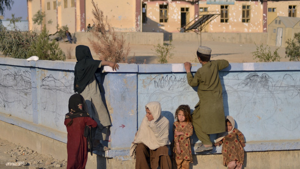Kinder sitzen an einer Wand in Afghanistan