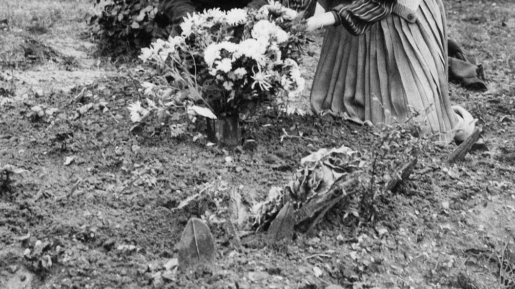 Altes Foto einer Grabstätte mit knieender Frau