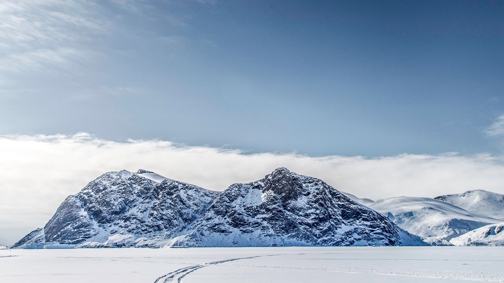 PICTUREDESK.COM/IMAGEBROKER/RUSSELL MILLNER Fahrspuren führen über einen gefrorenen Fjord in Richtung entfernter Berge, Baffin Island, Nunavut, Kanada, Nordamerika