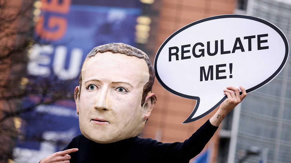 Demonstrant mit Plakat und Maske (Mark Zuckerberg):"Regulate me"