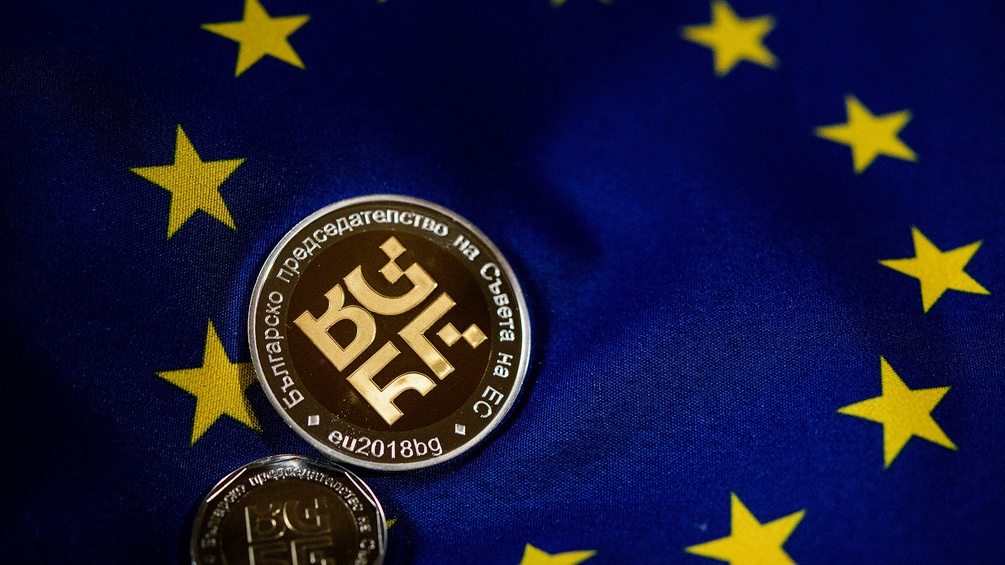 Goldmünze und EU-Flagge