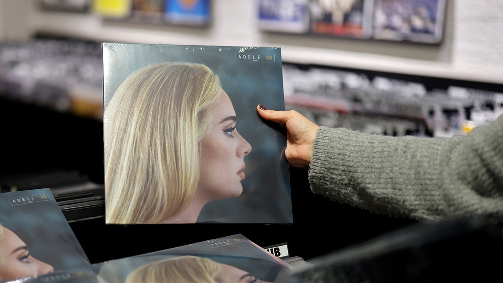 Eine Frau hält das Plattencover von Adele hoch.