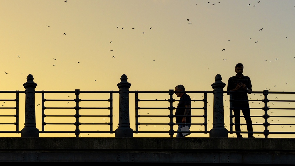 Zwei Personen auf einer Brücke im Gegenlicht