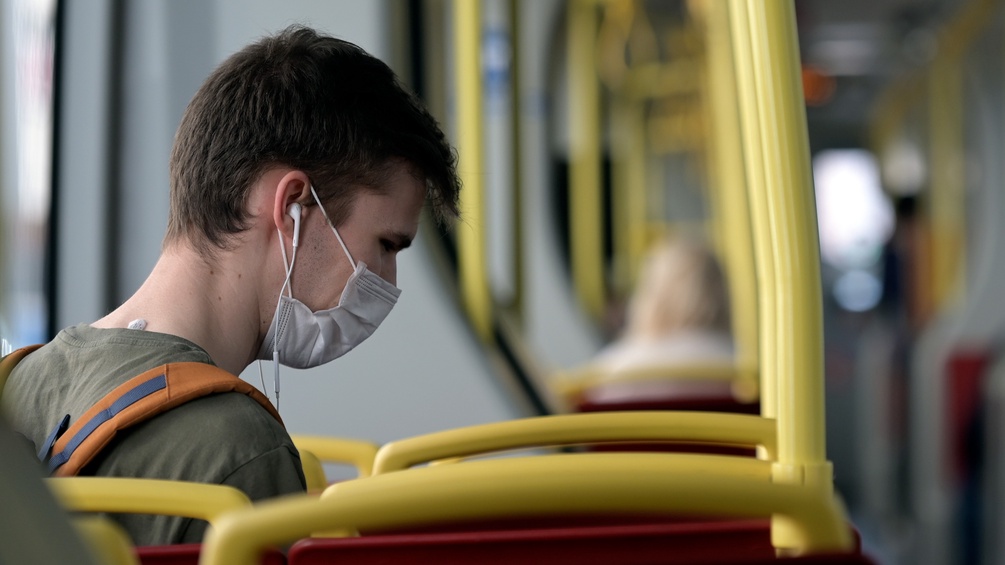 Junger Mann mit Maske in einem öffentlichen Verkehrsmittel