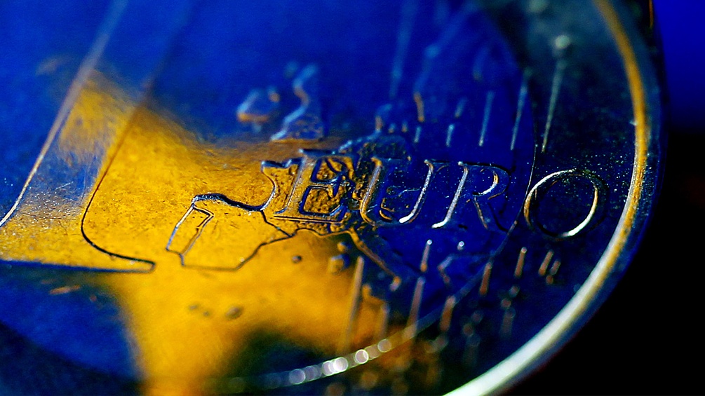 In einer Ein-Euro-Münze spiegelt sich der gelbe Stern der Europaflagge