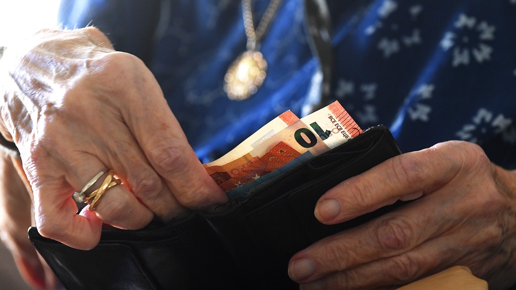 Ein Pensionistin öffnet ihre Geldbörse