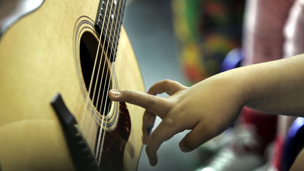 Kind greift nach Gitarrensaiten