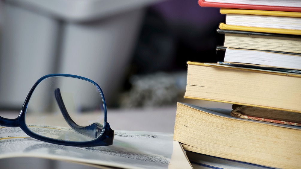 Brille neben Bücherstapel