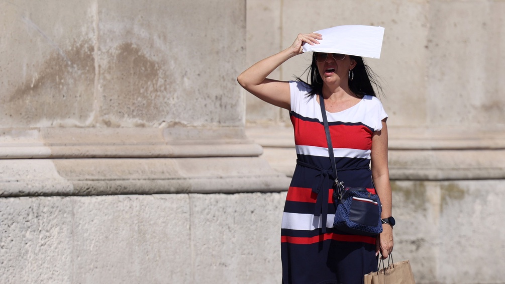 Frau macht sich mit einem Blatt Papier Schatten in der Pariser Sommerhitze
