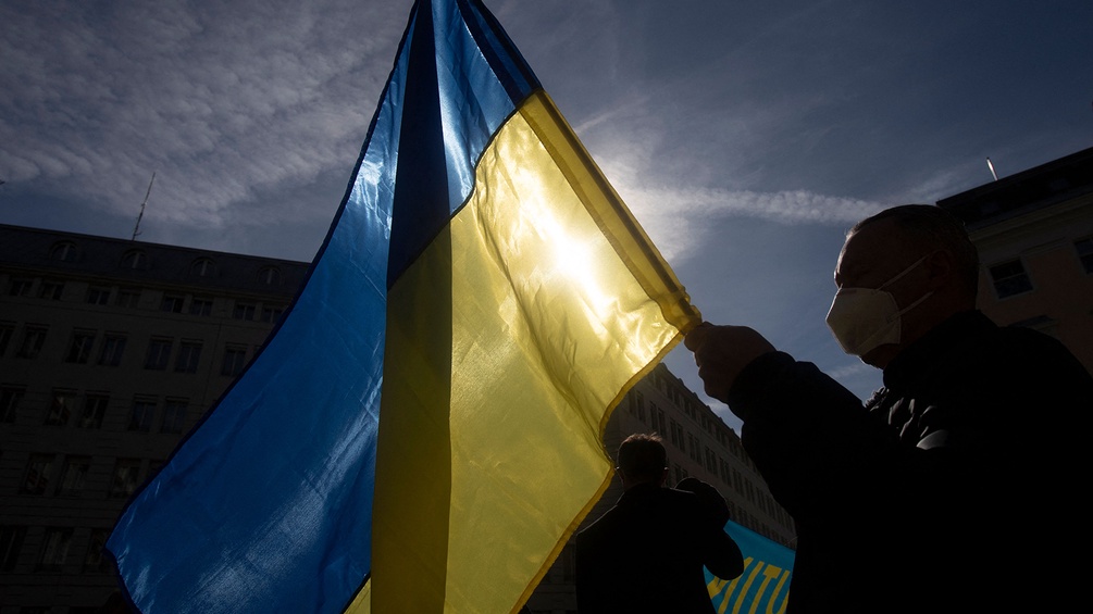 Ein Mann hält die Ukraine Fahne in die Luft.