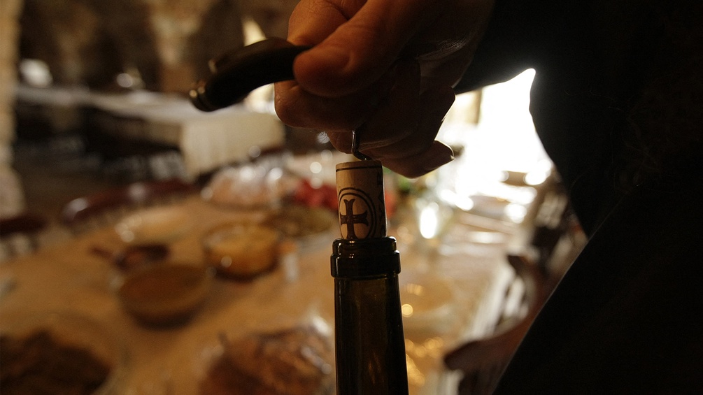 Ein Mönch öffnet eine Weinflasche.