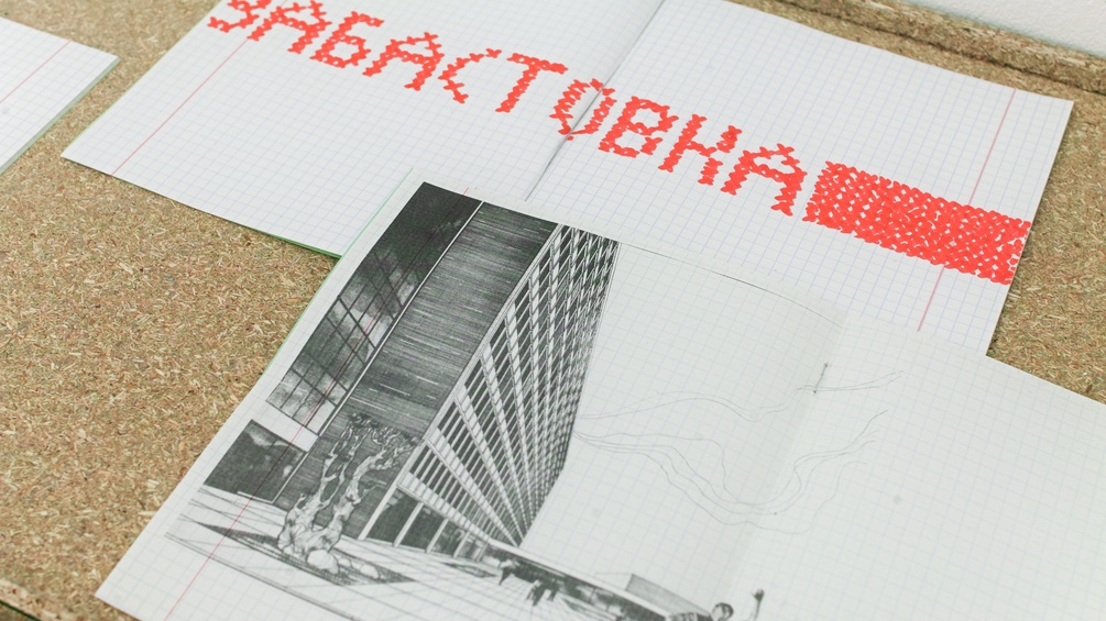 Schulheft mit einem Slogan der Proteste neben Schwarz-Weiß-Zeichnung einer Fabrik