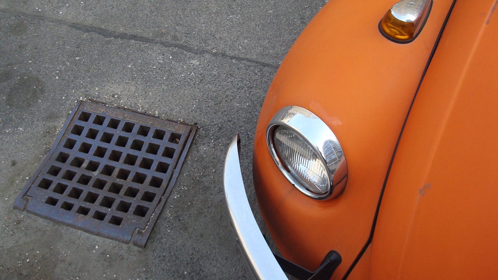 Ein orangefarbenes Auto und ein Gully