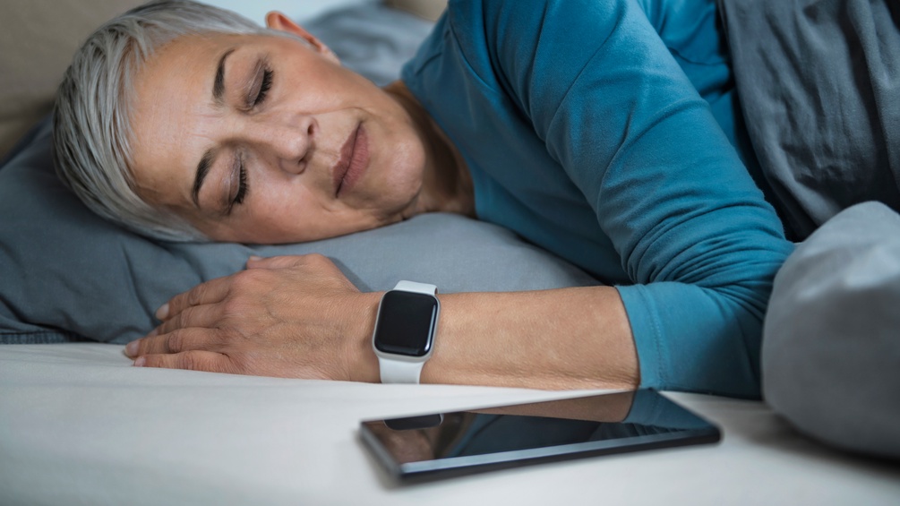 Schlafende Frau mit Smart Watch und Handy