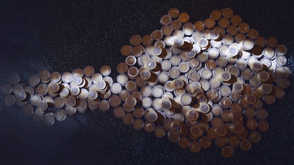 Euromünzen liegen in der Form Österreichs auf einem Tisch