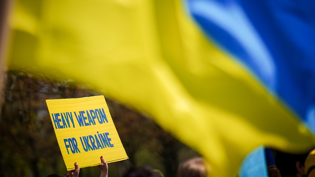 Ein Heavy Weapons Schild in den Farben der ukrainischen Flagge wird in die Höhe gehalten.