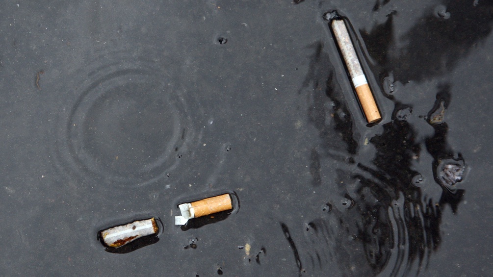Zigaretten liegen im Wasser am Boden.