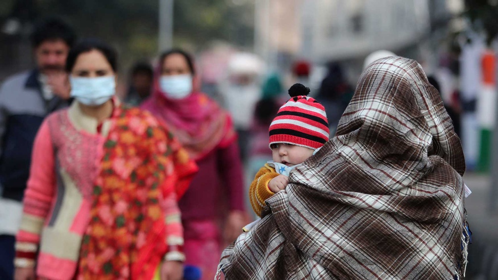 Frauen mit Mundschutz in Indien, Mutter trägt Kleinkind auf dem Arm