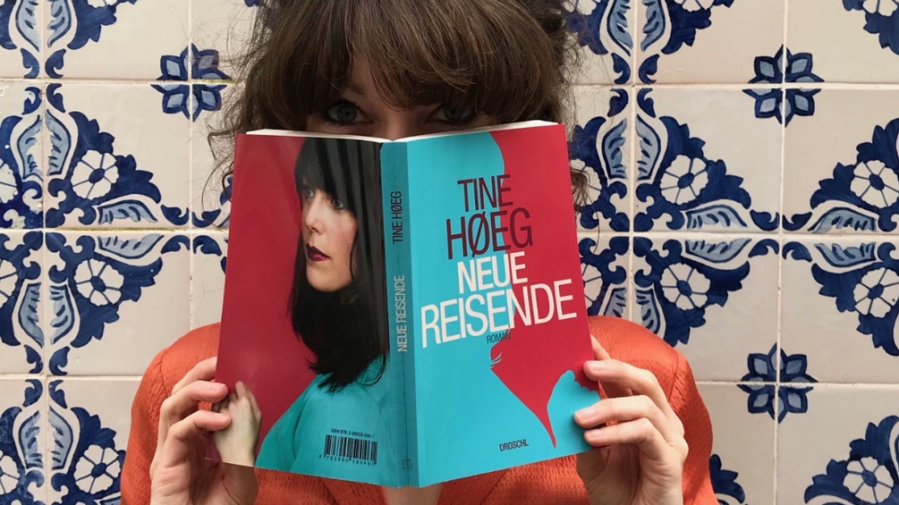 Tine Hoeg hält ihr Buch "Neue Reisende" vor ihr Gesicht.
