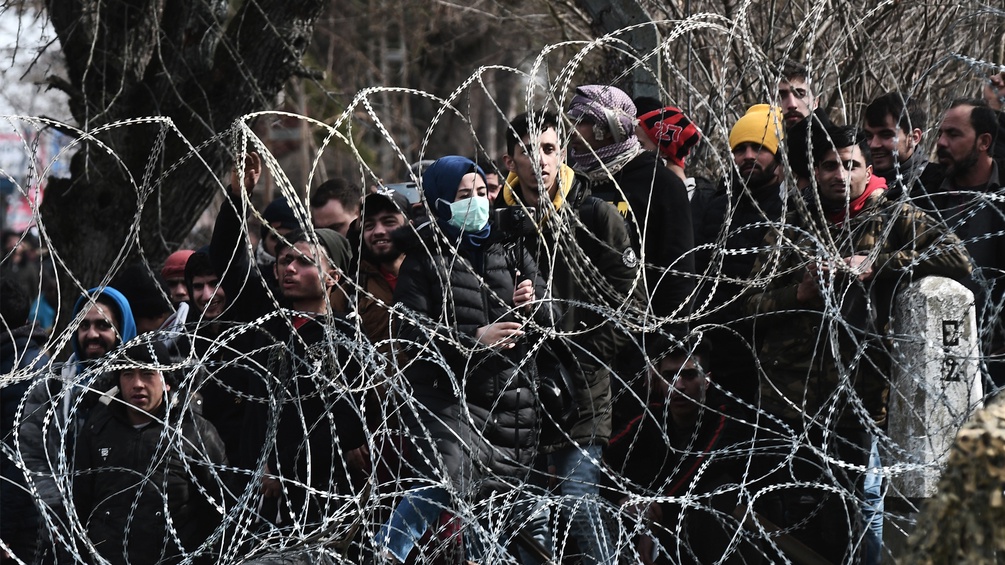 Menschen stehen an der Griechisch-türkischen Grenze hinter einem Maschendrahtzaun