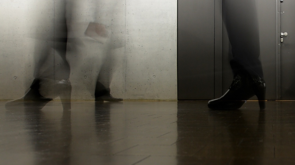 Verschwommene Füße von Menschen beim vorbeigehen vor einer Aufzugstür