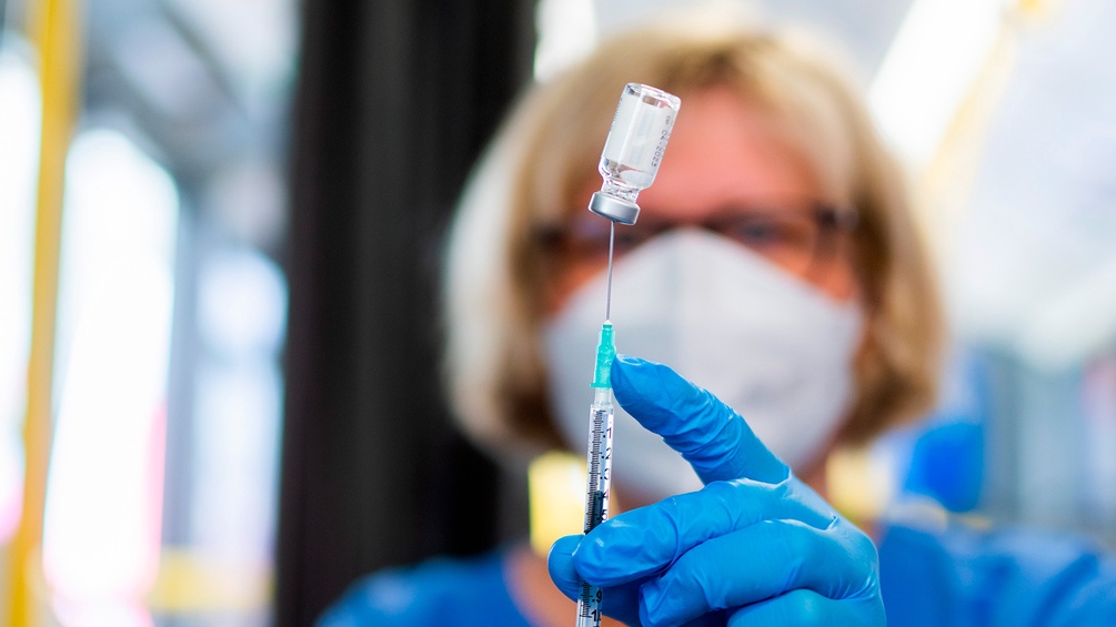Medizinisches Personal zieht eine Spritze mit einem Impfstoff gegen das Corona-Virus auf.