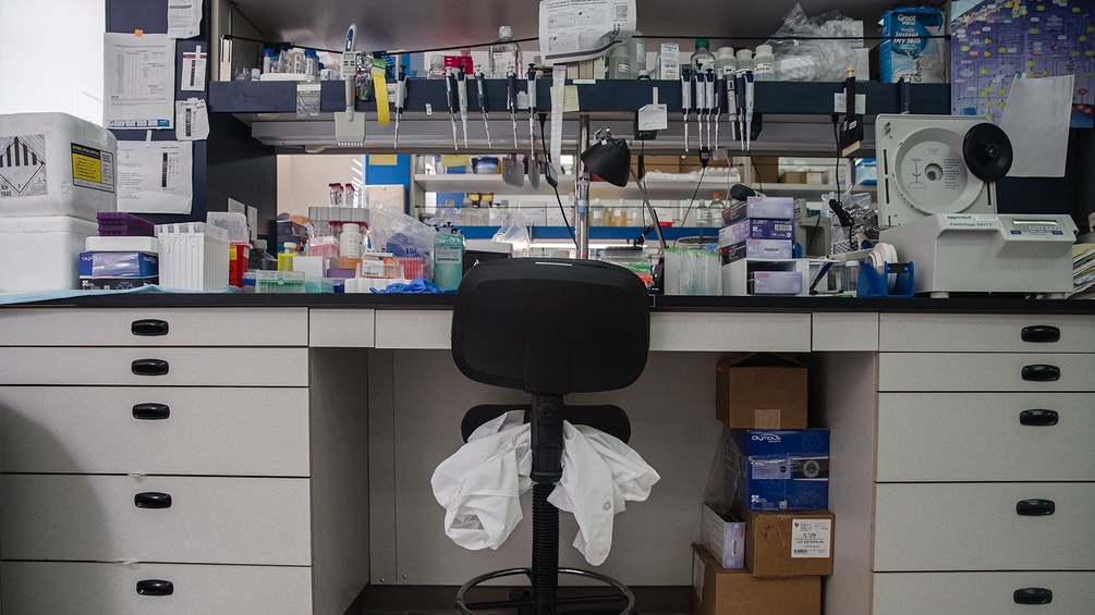 Ein Labormantel liegt auf einem Sessel in einem Labor.