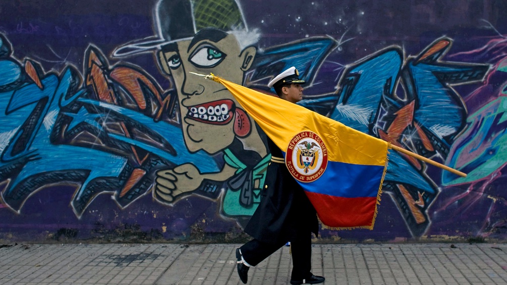 Kolumbianischer Militär mit Fahne vor Graffiti