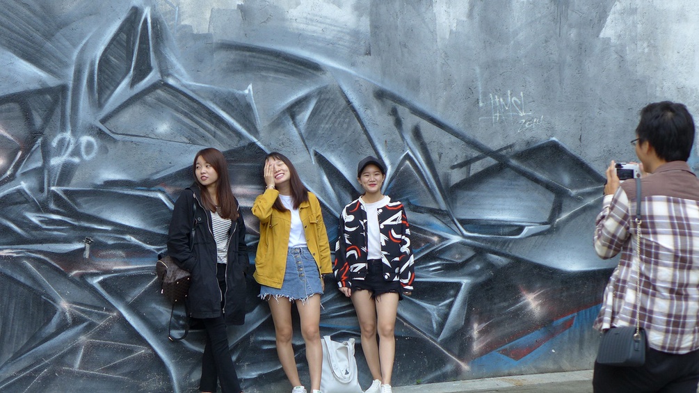 Drei chinesische Frauen posieren vor Graffiti
