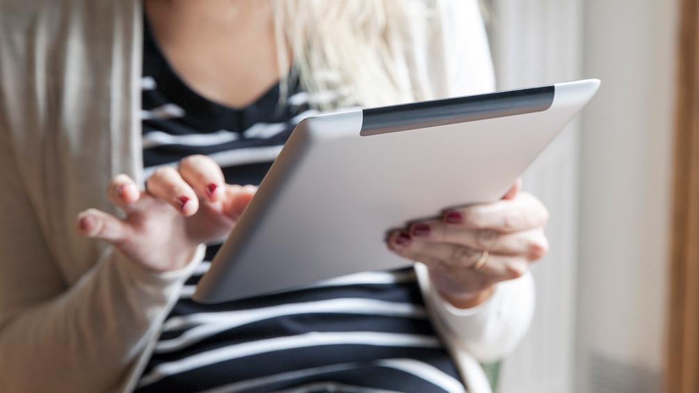 Frau hält ein Tablet und liest