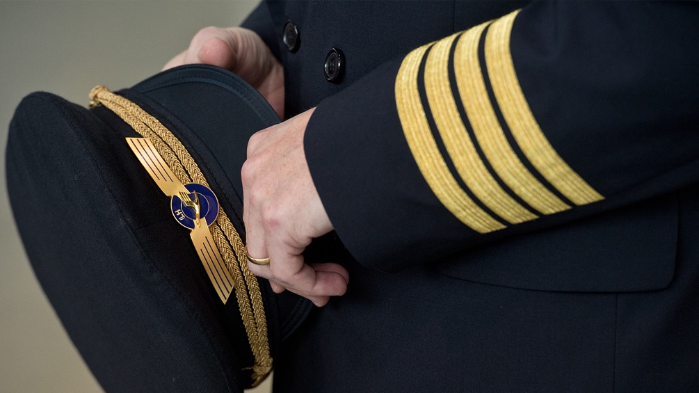 Ein Pilot hält seine Kappe resigniert vor sich.