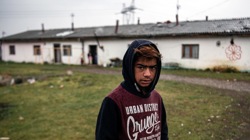 Roma im Kosovo vor einer Bungalowhausreihe