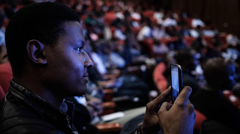 Keniascher Student blickt auf sein Smartphone