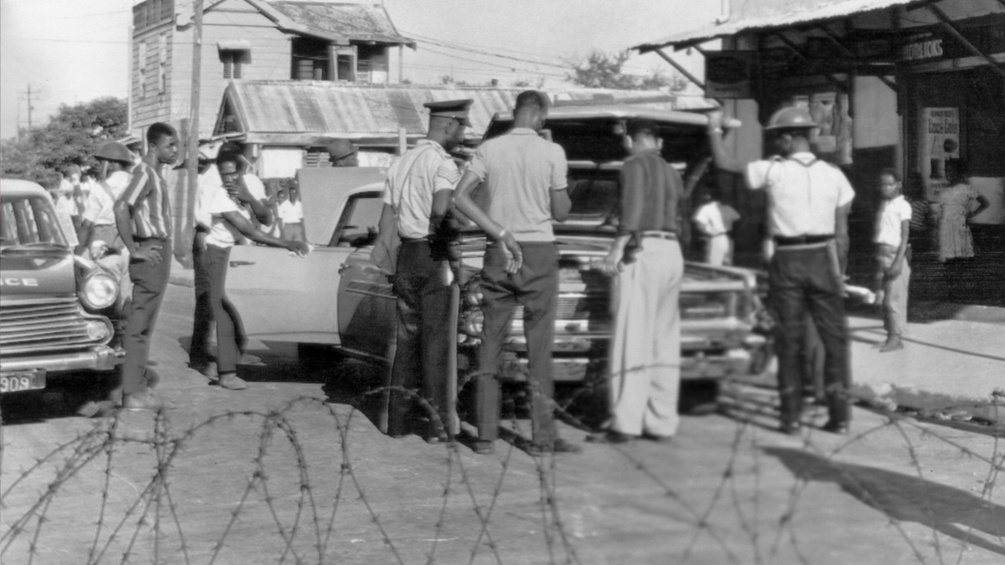 Jamaica um 1966 - merhere Männer werden durchsucht von einem Strassenpolizisten
