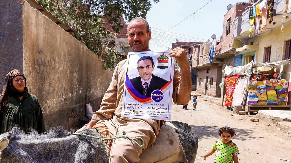Mann auf einem Esel hält ein Poster des Präsidenten Abdel Fattah al-Sisi hoch