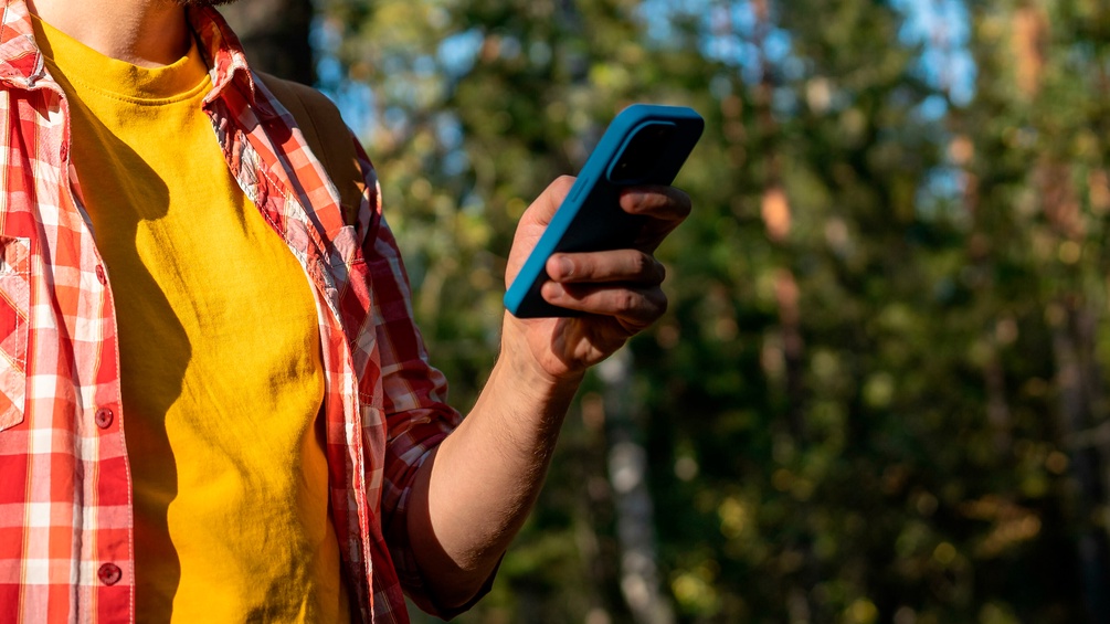 Mann mit Smartphone beim Wandern