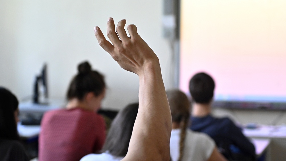 Eine aufzeigende Hand im Klassenzimmer