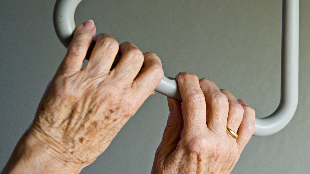 Hände einer alten Frau an einer Haltestange