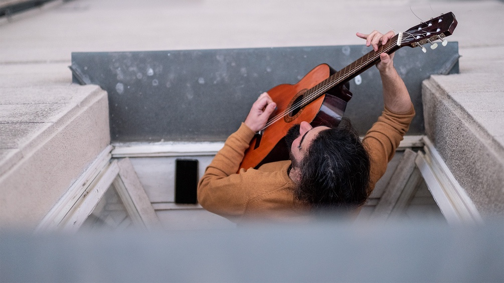 Musiker schaut aus dem Fenster mit Gitarre