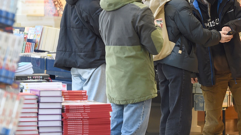 Menschen mit Handy in einer Buchhandlung