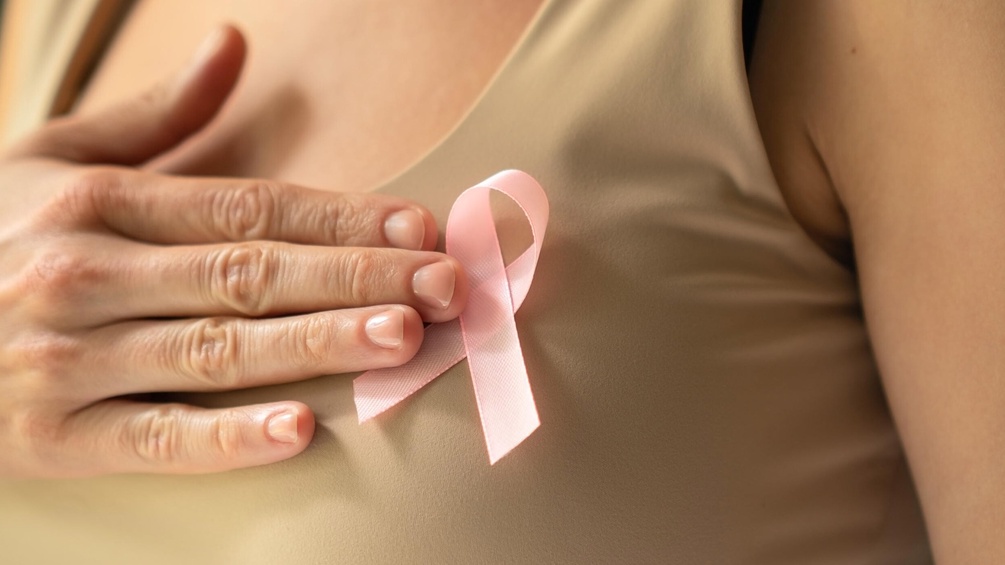 Weltbrustkrebstag: Frau hält rosa Masche an den Oberkörper