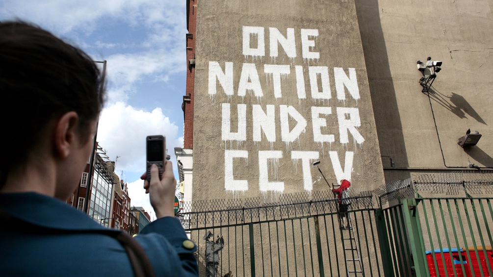 London, 2008: "One nation unter CCTV" an einer Hausmauer, daneben Überwachungscameras