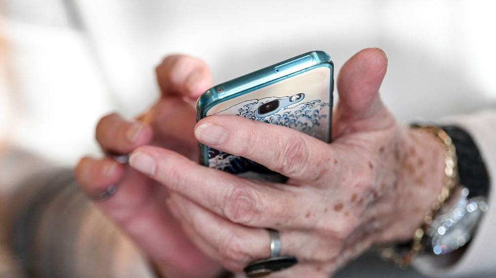 Die Hände einer älteren Dame mit einem Smartphone