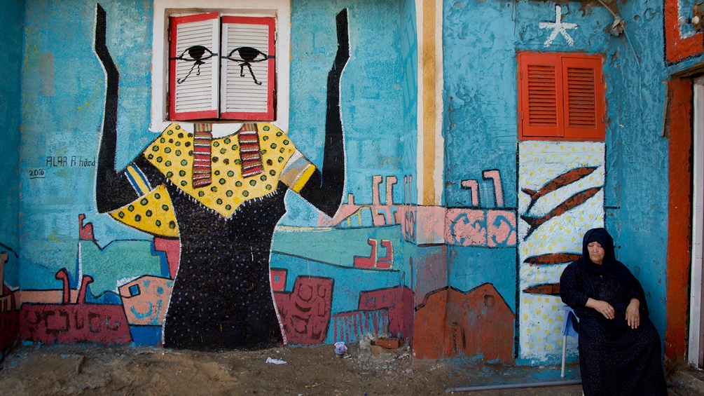 Eine ägyptische Frau sitzt vor einem Wandgemälde