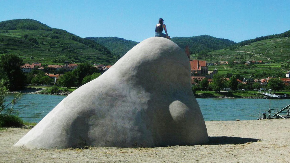 Eine Frau sitzt auf einer Nasenskulptur
